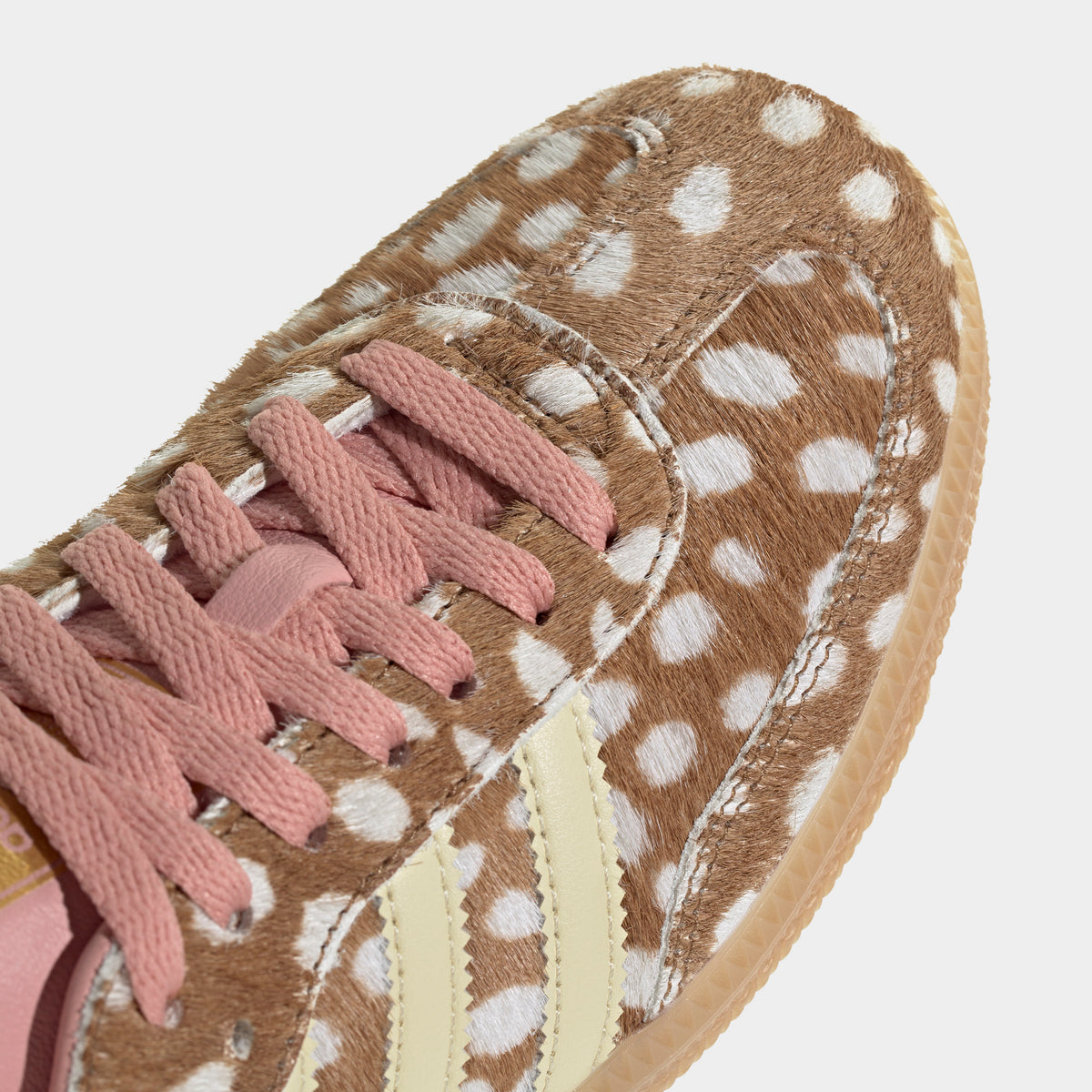 adidas Originals Women's Samba OG. Close-up view of the forefoot and eyestays highlighting the textured brown desert spotted ponyhair construction, dusty pink flat laces, and warm vanilla Three-Stripes. 