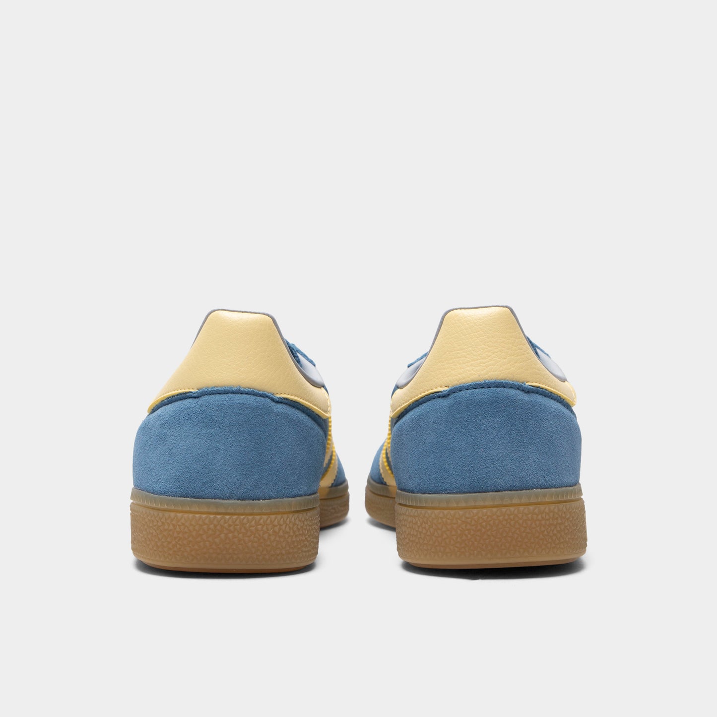 adidas Handball Spezial. Rear view of dusky ink, easy yellow and gum sneakers with yellow heel tabs, padded collars and gum soles.
