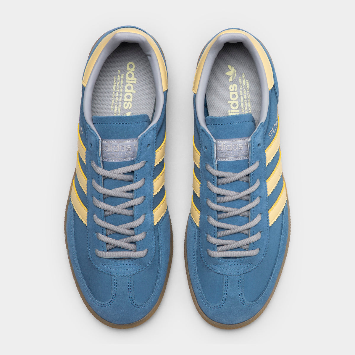 adidas Handball Spezial. Top view of dusky ink, easy yellow and gum sneakers showing blue laces, padded tongues and yellow collar details.