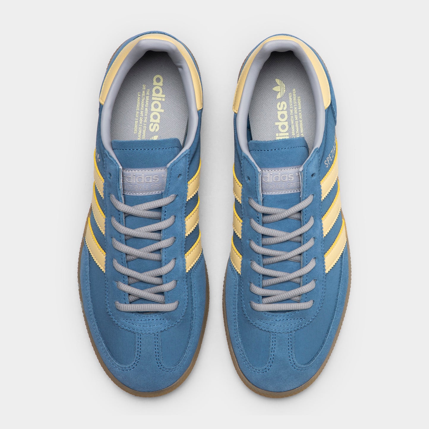 adidas Handball Spezial. Top view of dusky ink, easy yellow and gum sneakers showing blue laces, padded tongues and yellow collar details.