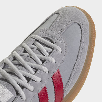adidas Handball Spezial. Close-up of halo silver, team victory red and gum sneaker showing grey laces, suede toe overlay and red stripes.