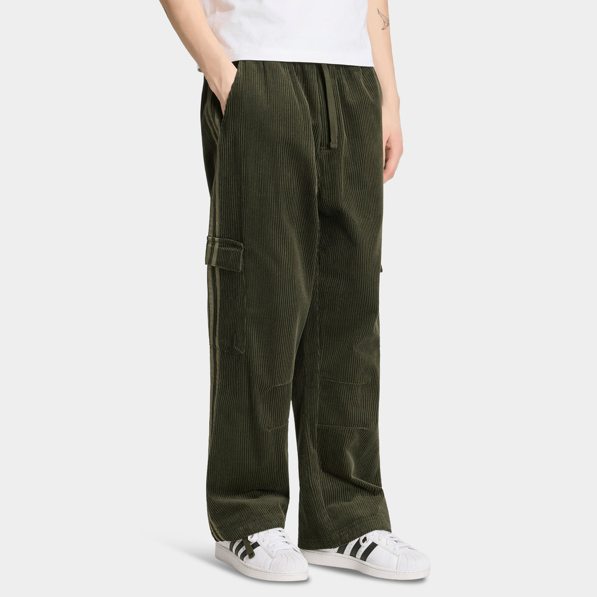 adidas Adicolor Cord Cargo Pants. Front view of night cargo corduroy pants with wide legs, elastic waistband and large side cargo pockets.