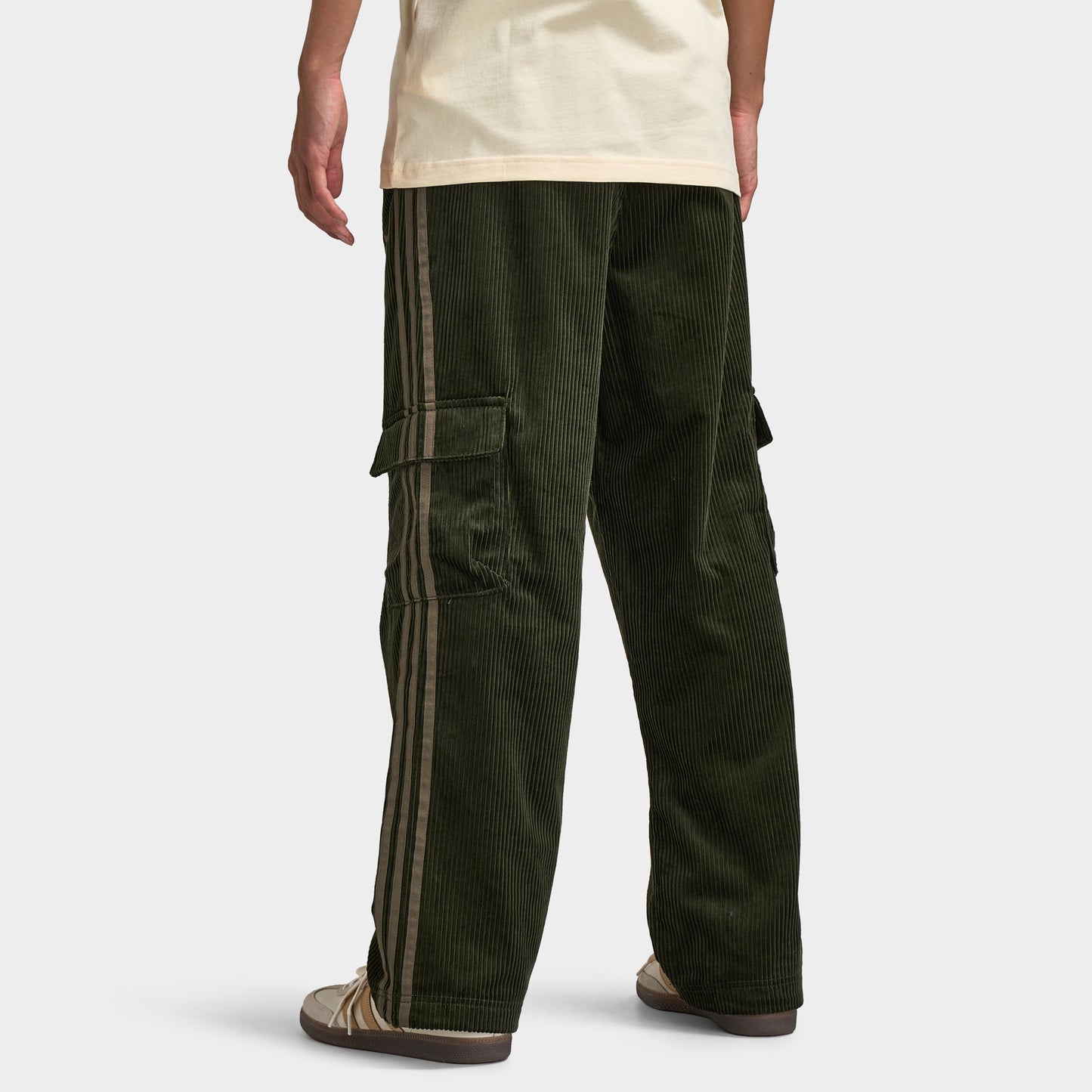 adidas Adicolor Cord Cargo Pants. Back view of model wearing night cargo corduroy pants with wide legs, rear pockets and relaxed silhouette.