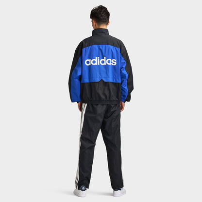 adidas Munich 93 Tracktop. Full-body back view of model wearing blue and black track jacket with large white adidas branding and matching black pants.