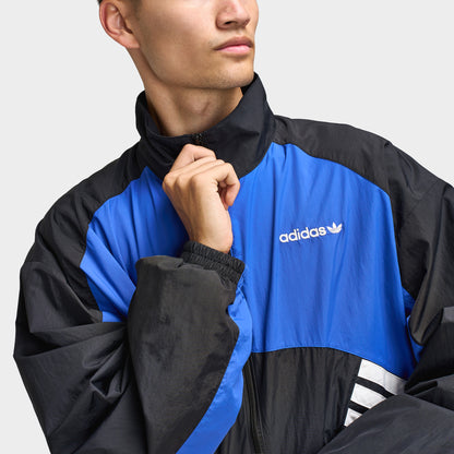 adidas Munich 93 Tracktop. Close-up of blue and black track jacket showing high collar, full-zip closure and contrast panel construction.