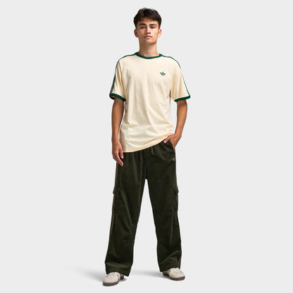 adidas 3 Stripes T-Shirt. Full-body front view of model wearing vanilla and collegiate green T-shirt with dark green pants and light-coloured shoes.