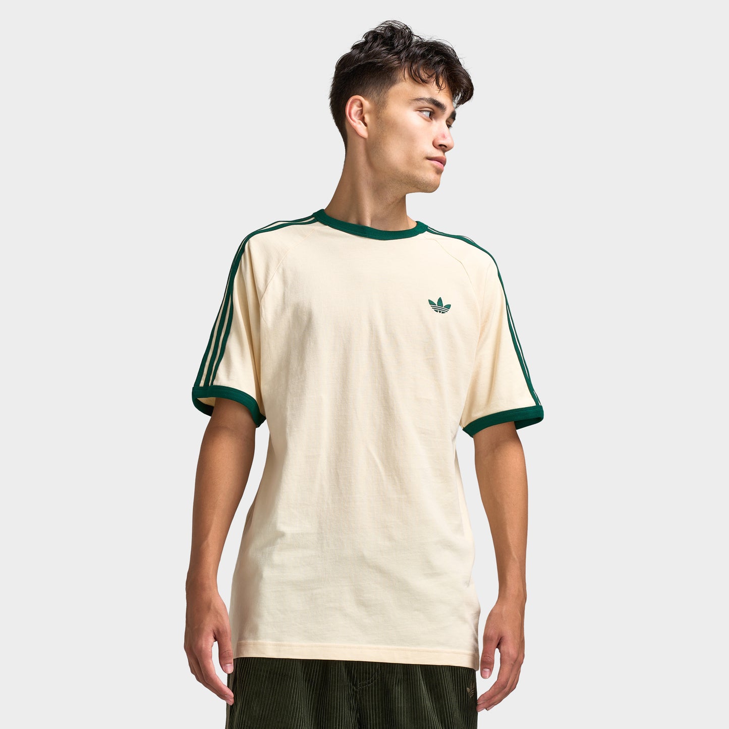 adidas 3 Stripes T-Shirt. Front view of model wearing vanilla and collegiate green T-shirt with green collar trim, green sleeve stripes and small Trefoil chest logo.