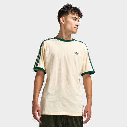 adidas 3 Stripes T-Shirt. Front view of model wearing vanilla and collegiate green T-shirt with green collar trim, green sleeve stripes and small Trefoil chest logo.