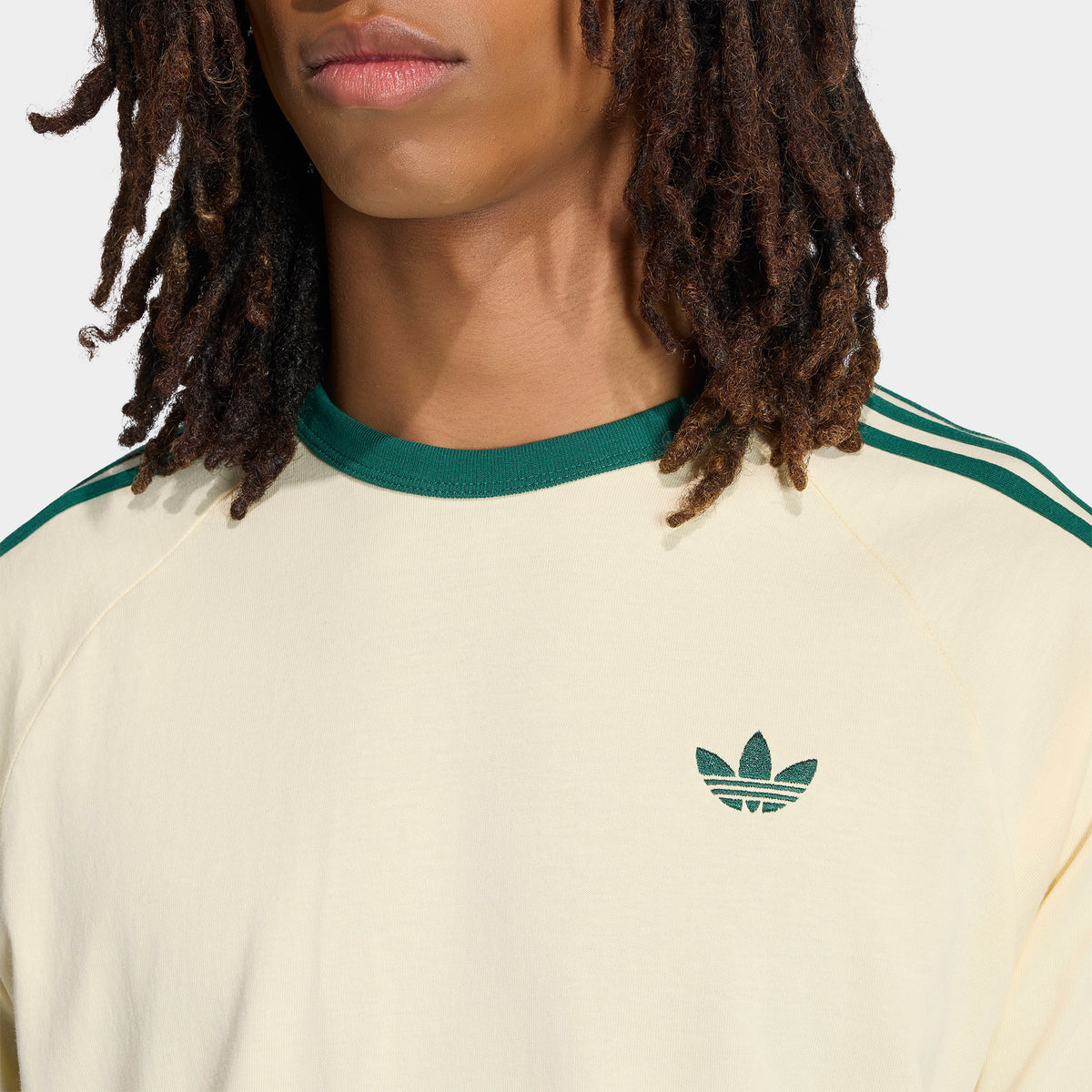 adidas 3 Stripes T-Shirt. Close-up of vanilla and collegiate green T-shirt showing green collar trim, three shoulder stripes and Trefoil chest logo.