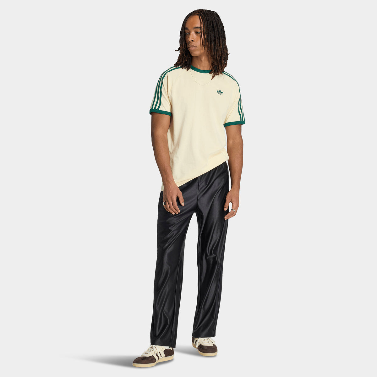 adidas 3 Stripes T-Shirt. Full-body view of model wearing vanilla and collegiate green T-shirt with black pants and light-coloured shoes.