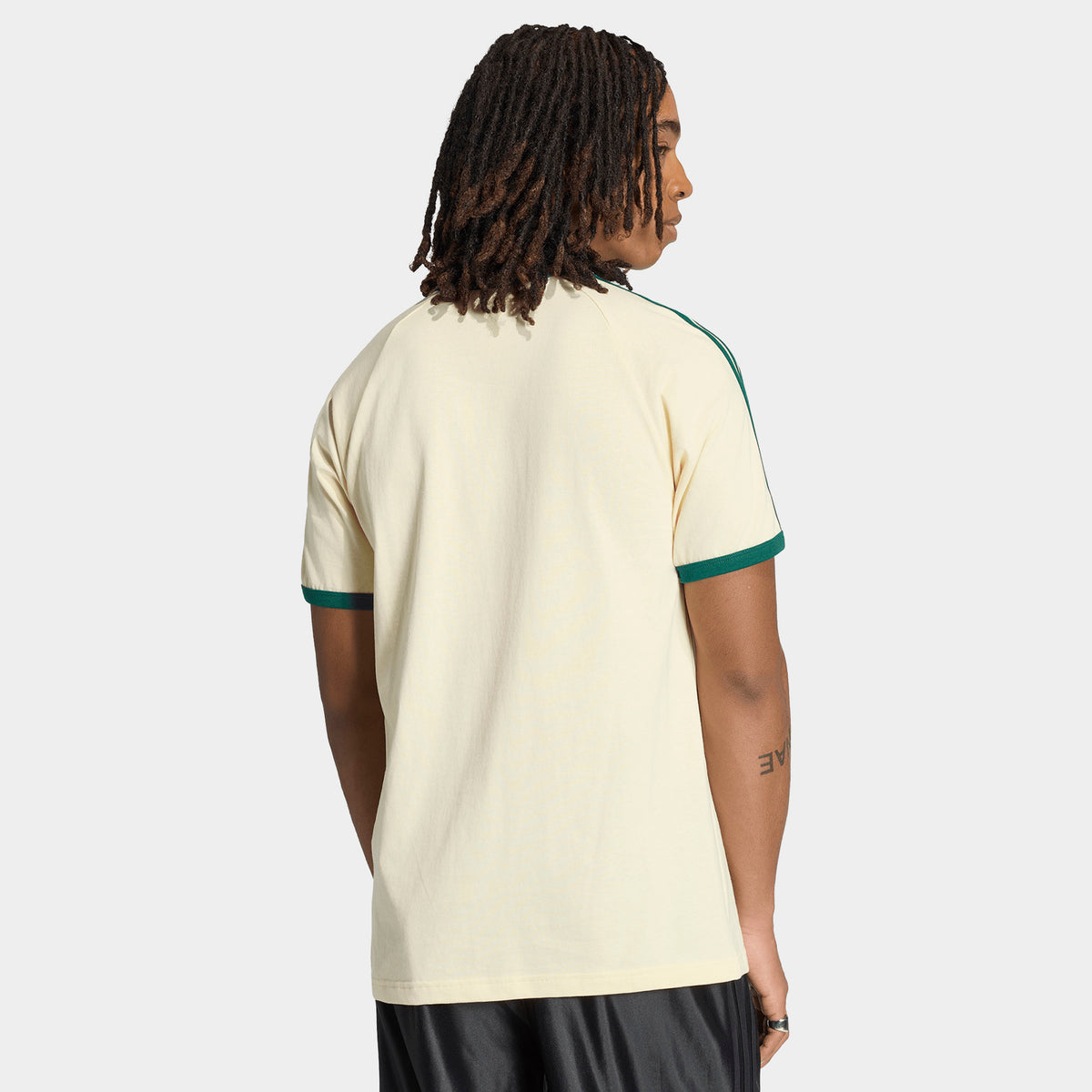 adidas 3 Stripes T-Shirt. Back view of model wearing vanilla and collegiate green T-shirt with plain back and green sleeve trim.