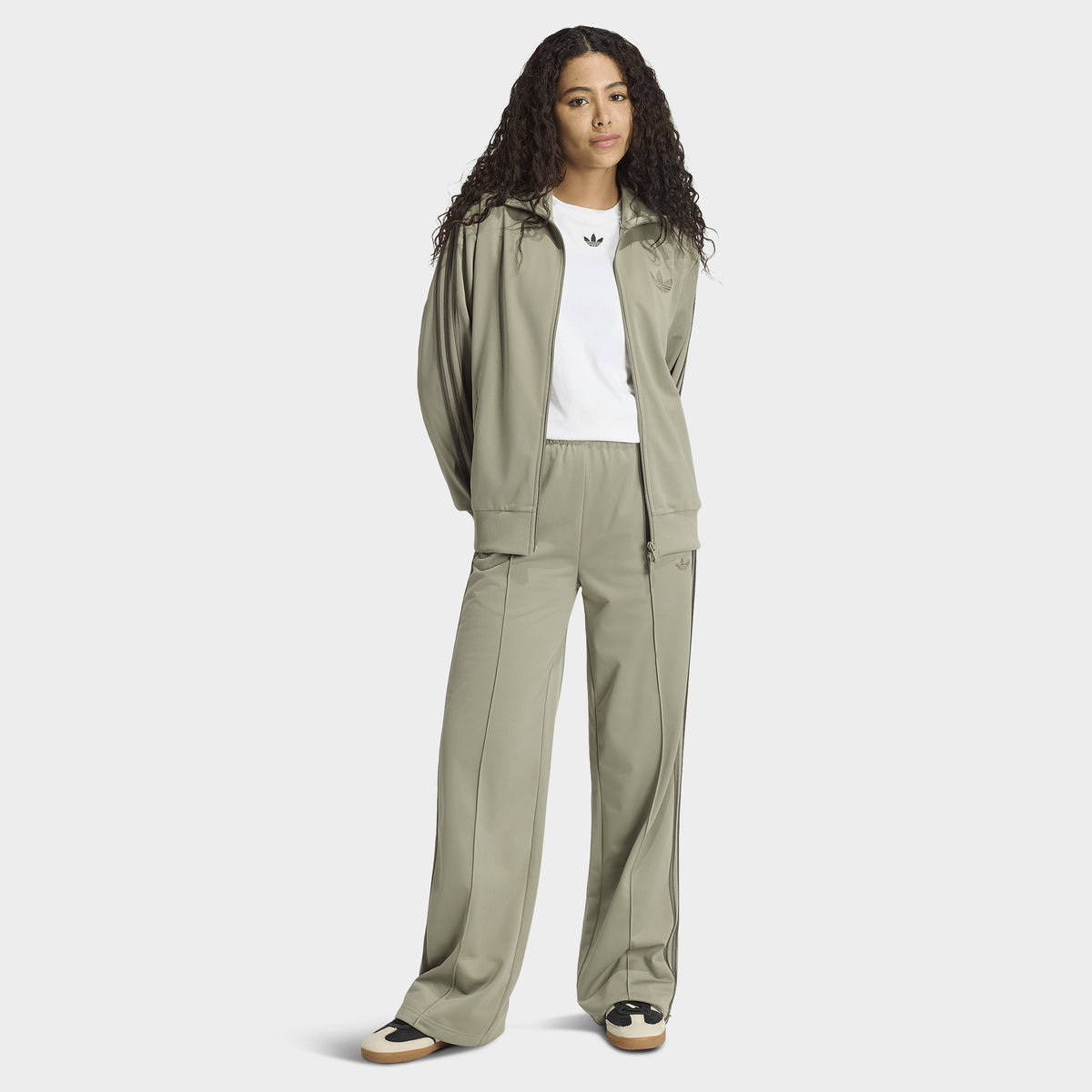 adidas Firebird Loose Track Pants. Full-body view of model wearing silver-pebble branch track pants with matching jacket and sneakers.