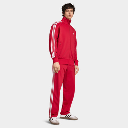 adidas Firebird Track Top. Full-body view of model wearing team victory red track jacket with matching pants and white sleeve stripes.