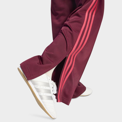 adidas Firebird Loose Track Pant. Close-up of maroon track pants showing the power pink side stripes and loose hem.
