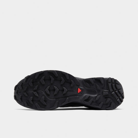 Salomon XT-6. Bottom view of black and phantom trail sneaker showing black lugged outsole with red centre detail.