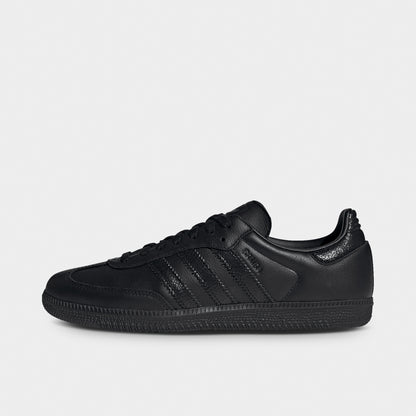 adidas Samba OG. Side view of black sneaker with tonal three stripes, stitched overlays and black gum-style sole.