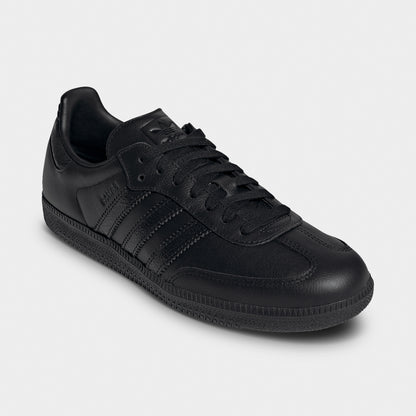 adidas Samba OG. Three-quarter view of black sneakers with black laces, tonal stripes and low-profile soles.