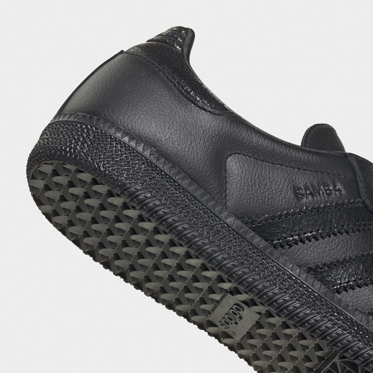 adidas Samba OG. Close-up of black sneaker showing tonal heel panel, side branding and textured outsole edge.