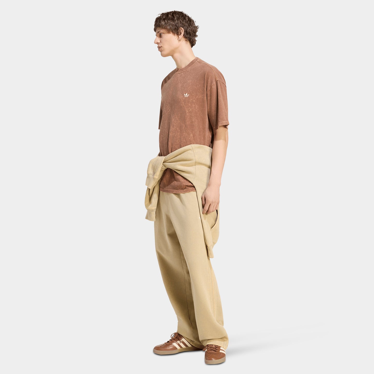adidas Trefoil Essential Washed Loose T-Shirt. Full-body view of model wearing preloved brown T-shirt with beige pants and light-coloured shoes.