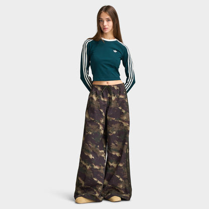 adidas Women's Camouflage Adilenium Track Pant. Full-length front model view of night cargo, aurora coffee, and olive strata camouflage wide-leg track pants, styled.  