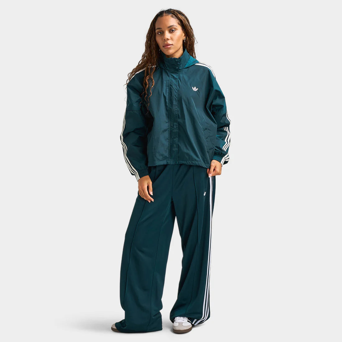 Woman wears adidas Women’s Adicolor 3‑Stripes Woven Windbreaker “Ivy / White” jacket. Shop Women’s Clothing now at JD Sports.