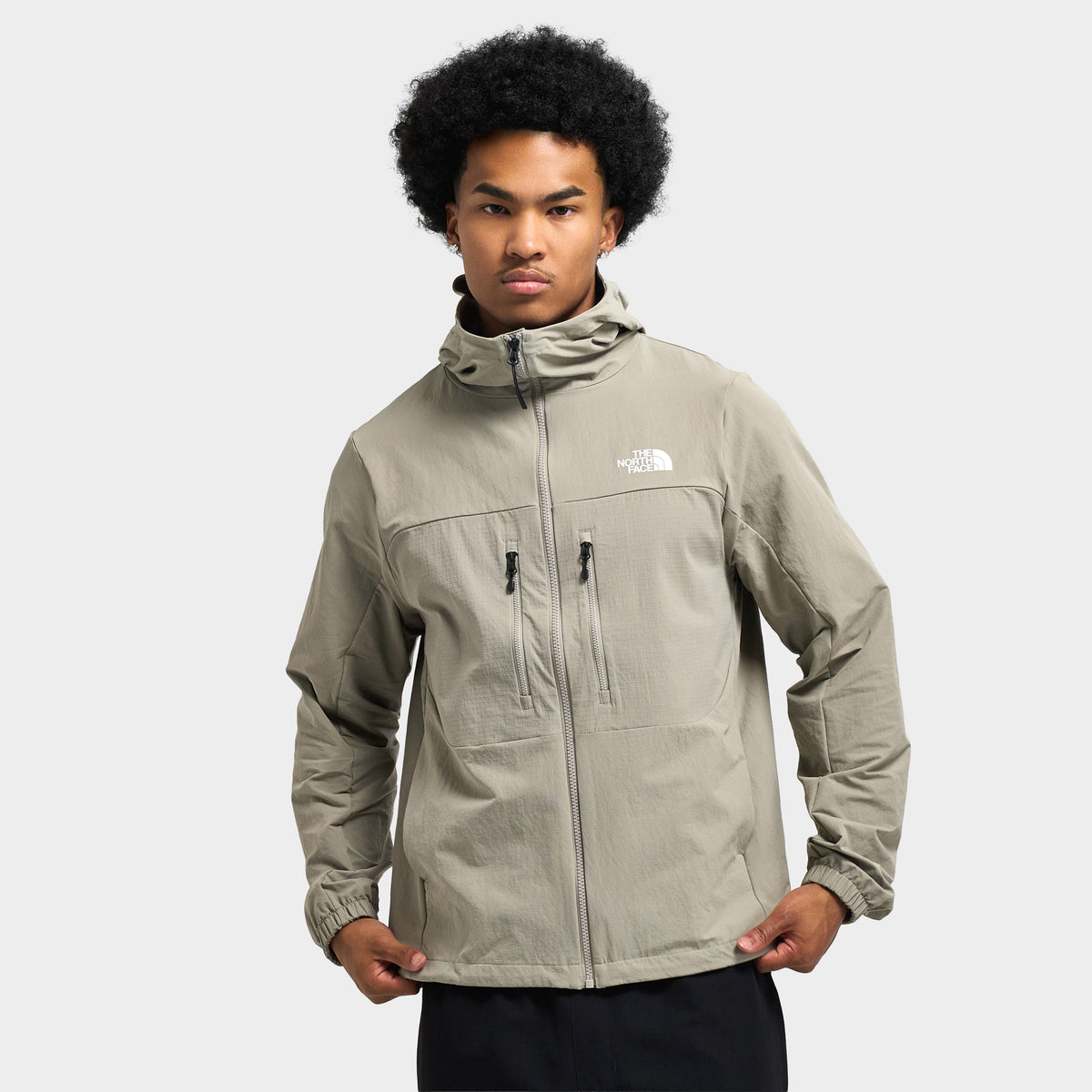 The North Face Trishull Full-Zip Jacket. Stone slab grey hooded jacket featuring full front zip, dual zippered chest pockets, high collar, and white logo. 