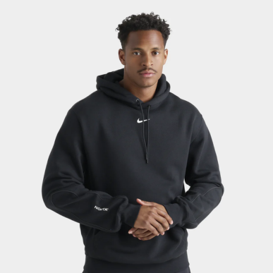 Man wears Nike NOCTA Cardinal Fleece Pullover Hoodie "Black / White". Shop Men's Clothing now