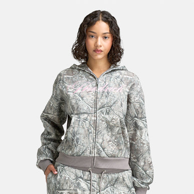 Woman wears Hoodrich Women's Mid Length Zip Through Hoodie "Woodland Camo". Shop Women's Clothing now.