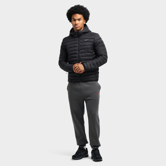 Sonneti Cargo Jacket. Full-length front view of model wearing black lightweight puffer jacket paired with dark grey sweatpants and black sneakers. 