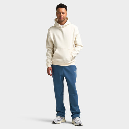 Sonneti London Hoodie 2.0. Full-body front view of model wearing egret hoodie with blue pants and white sneakers.