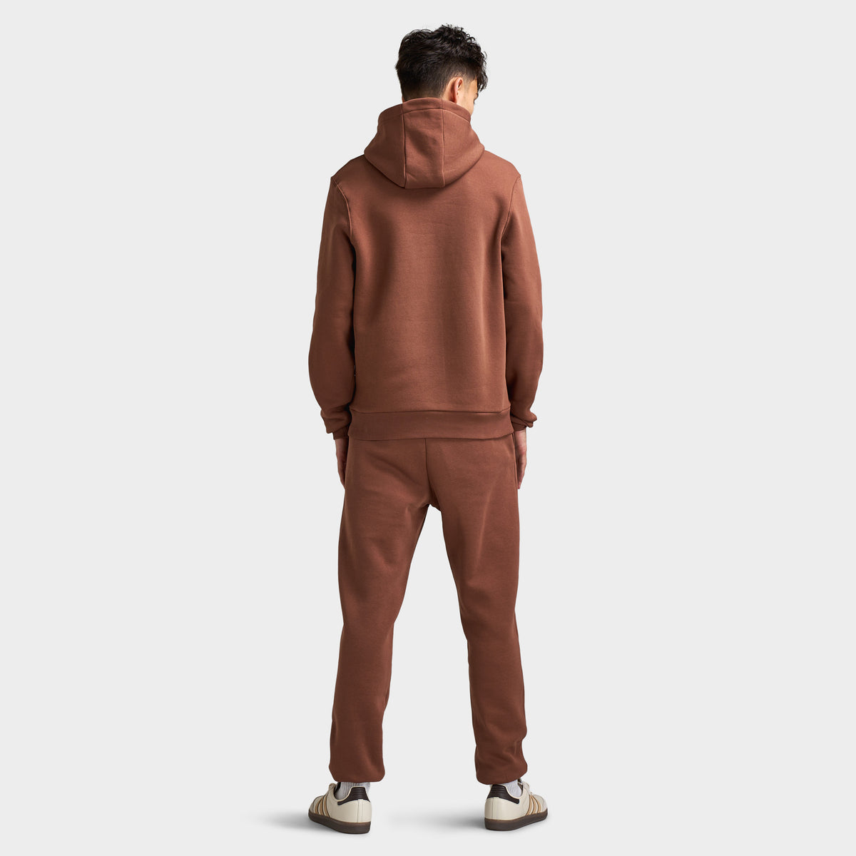 Sonneti London Hoodie 2.0. Full-body back view of model wearing cocoa brown hoodie with raised hood, matching pants and white sneakers.