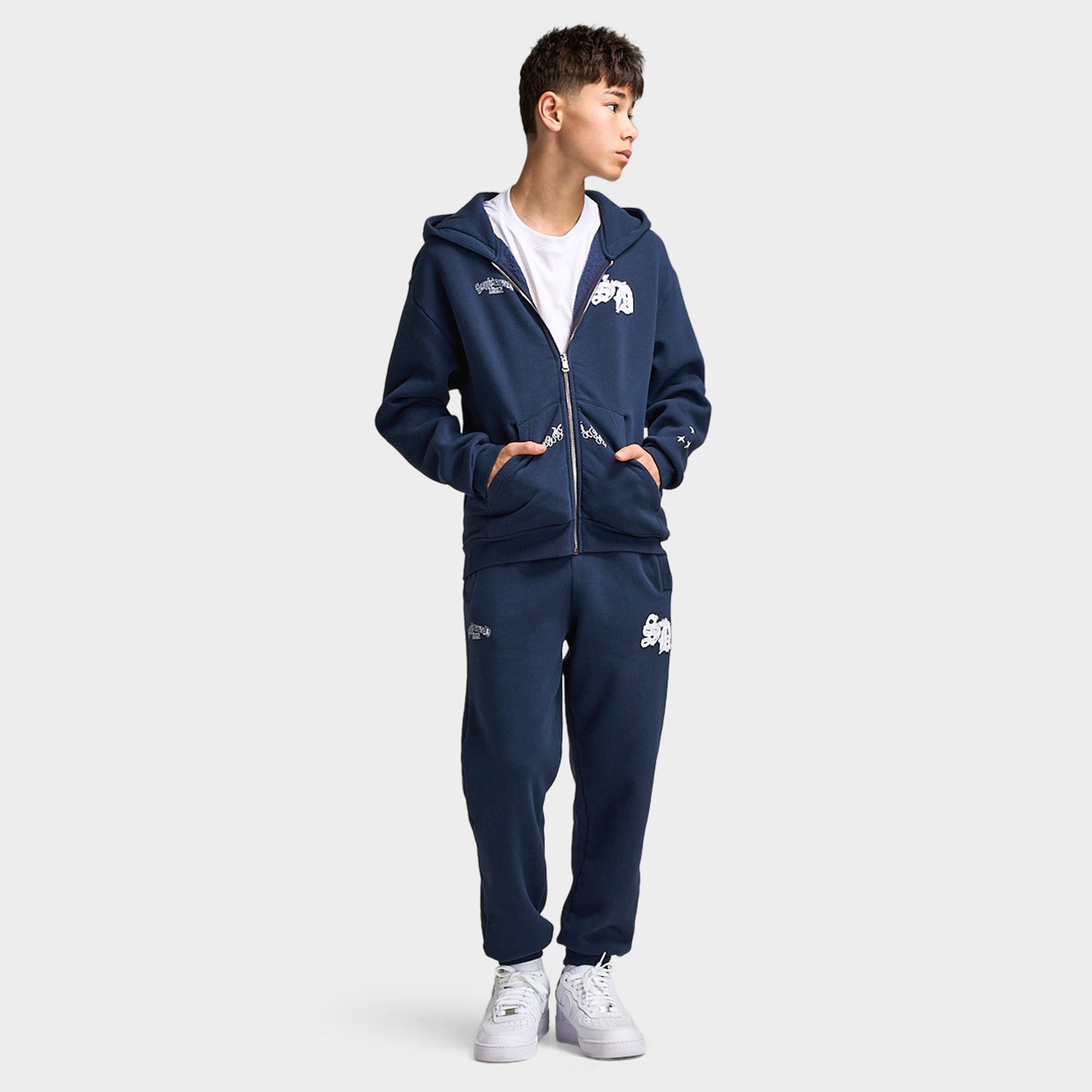 Supply & Demand Juniors' Scape Hoodie. Full-body front view of model wearing washed navy hoodie with matching pants and white sneakers.