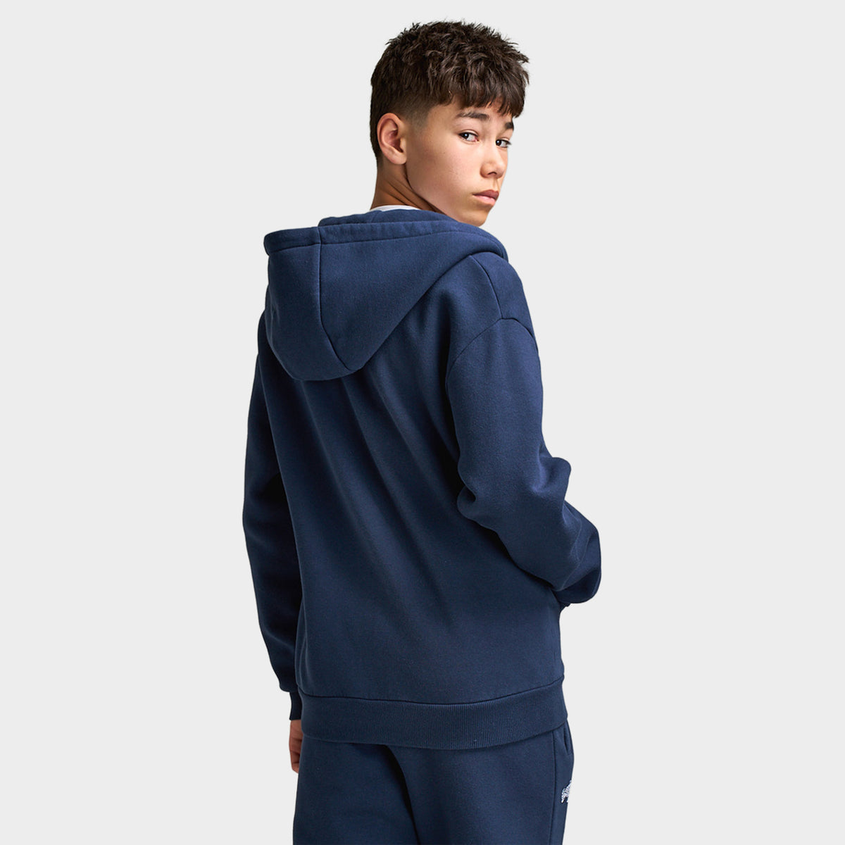 Supply & Demand Juniors' Scape Hoodie. Back three-quarter view of model wearing washed navy hoodie with raised hood and relaxed fit.