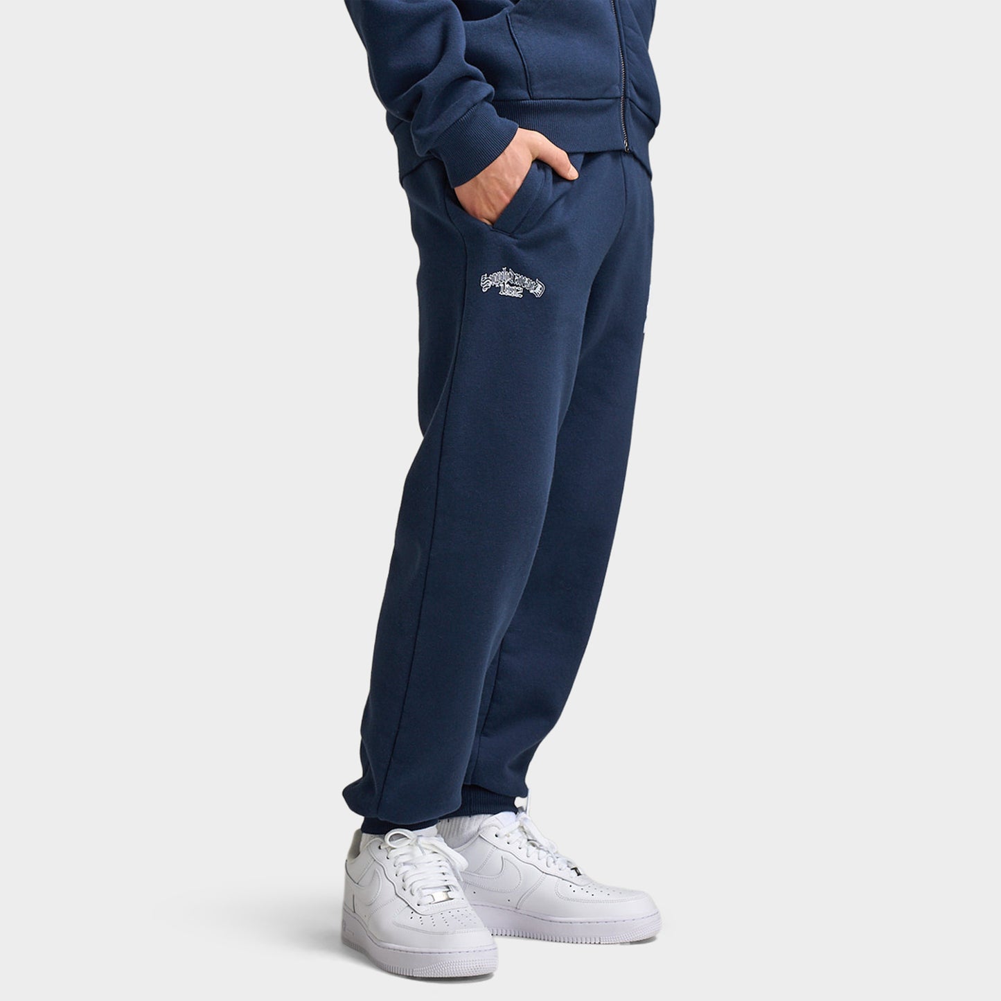 Supply & Demand Juniors' Scape Pants. Three-quarter view of model wearing washed navy pants with elastic cuffs, side pockets and relaxed fit.