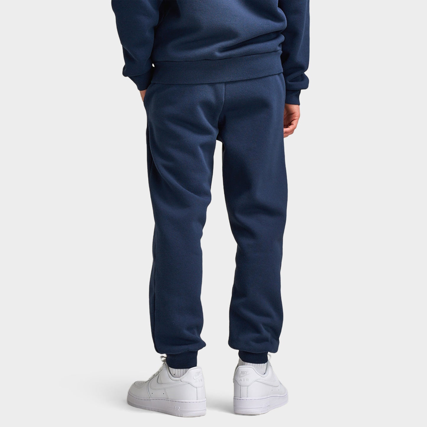 Supply & Demand Juniors' Scape Pants. Back view of model wearing washed navy pants with tapered legs, elastic cuffs and plain rear panels.