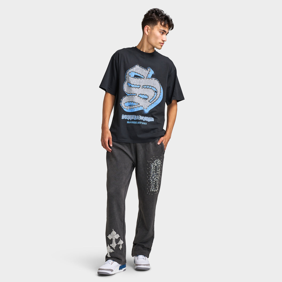 Supply & Demand Murphy Oversized Pants. Full-body view of model wearing black oversized pants with a graphic T-shirt and sneakers.