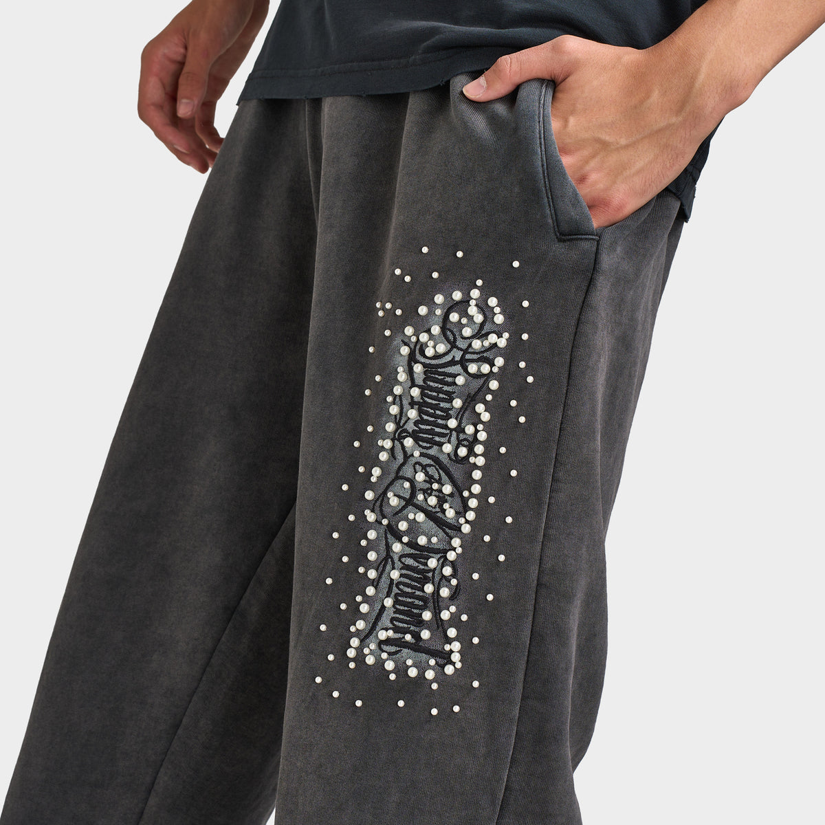 Supply & Demand Murphy Oversized Pants. Close-up of black oversized pants showing side pocket, washed texture and large white graphic print.