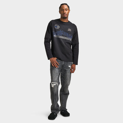 Supply & Demand Global Longsleeve Tee. Full-body front view of model wearing black long-sleeve T-shirt with distressed black jeans and dark shoes.