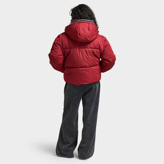 Supply & Demand Women's Macy Jacket. Full-body back view of model wearing pomegranate puffer jacket with dark pants and sneakers.