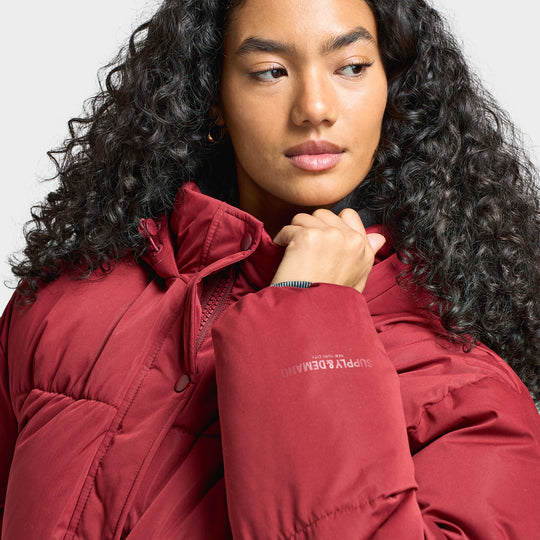 Supply & Demand Women's Macy Jacket. Close-up front view of pomegranate puffer jacket showing the high collar, padded construction and zip closure.