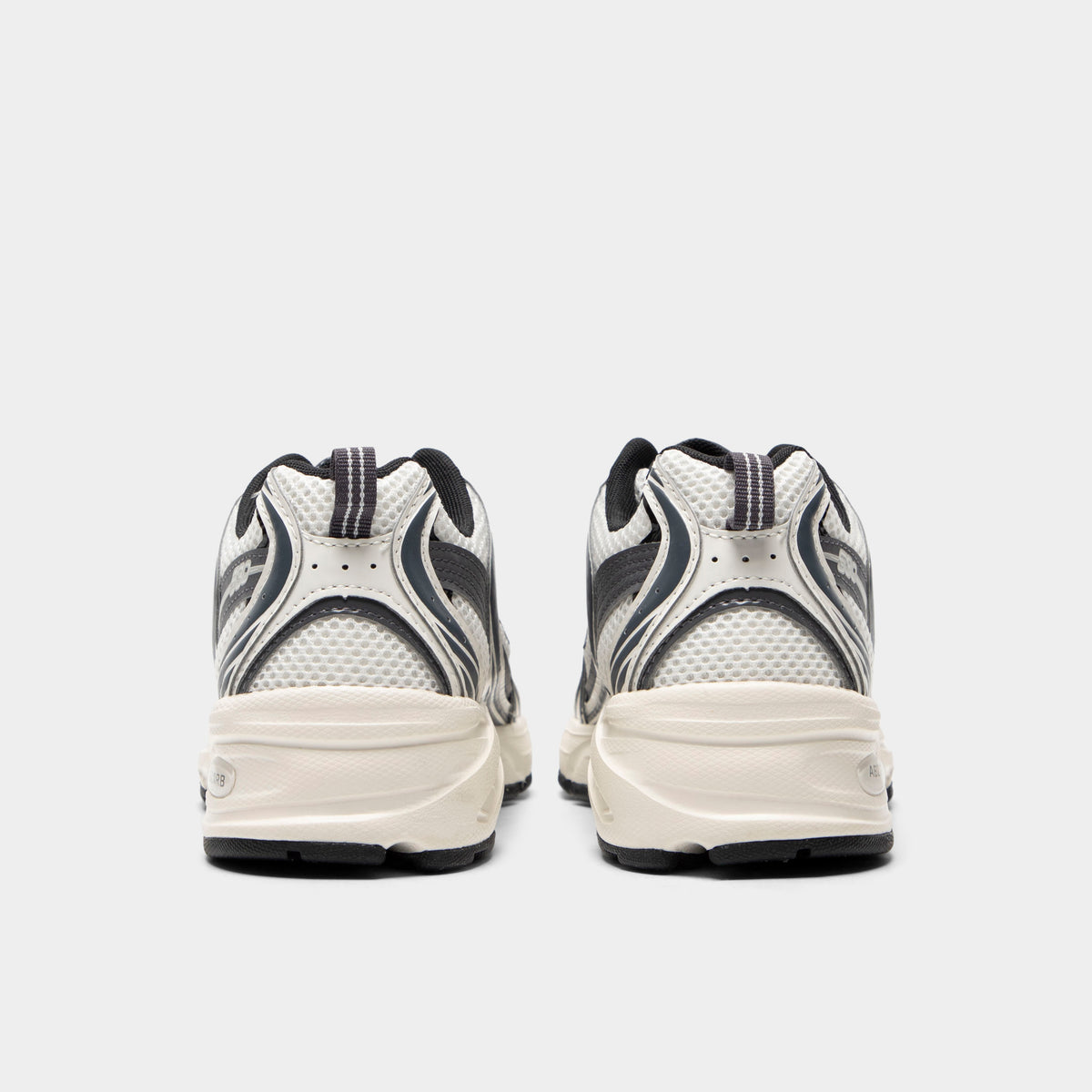 New Balance 530. Rear view of sea salt and magnet sneakers with padded heel panels, layered detailing and light midsoles.