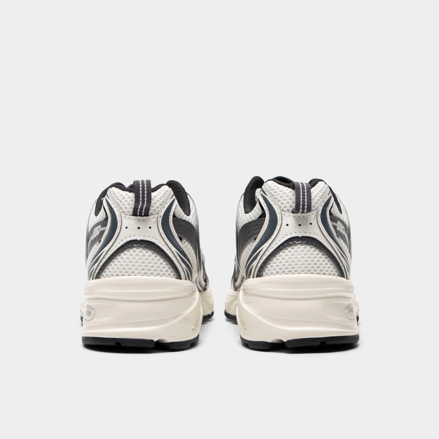 New Balance 530. Rear view of sea salt and magnet sneakers with padded heel panels, layered detailing and light midsoles.