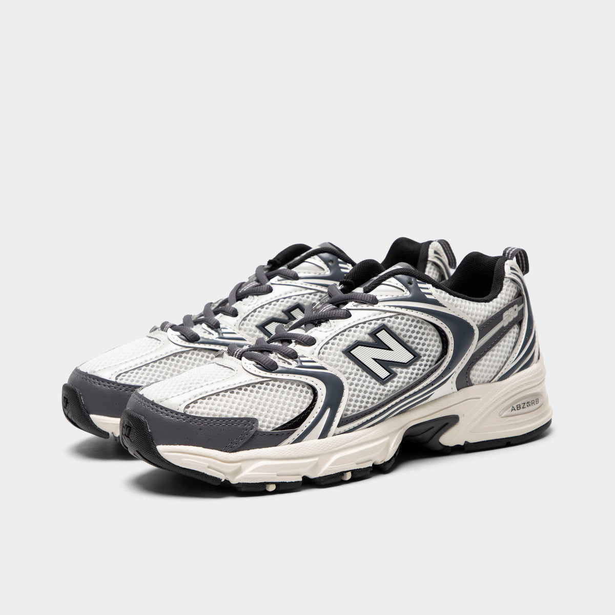 New Balance 530. Three-quarter view of sea salt and magnet sneakers with grey laces, layered overlays and dark N branding.