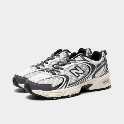 New Balance 530. Three-quarter view of sea salt and magnet sneakers with grey laces, layered overlays and dark N branding.