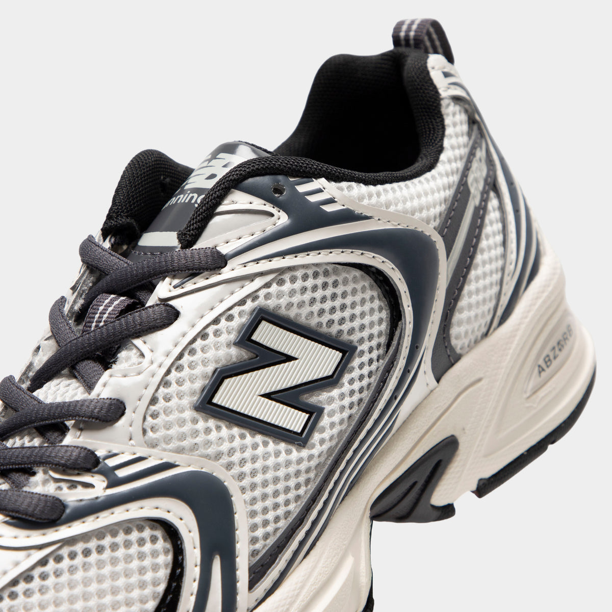 New Balance 530. Close-up of sea salt and magnet sneaker showing grey laces, mesh panels, layered overlays and N logo.