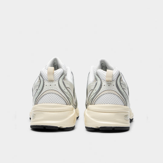 New Balance 530. Rear view of silver metallic and linen sneakers with padded heel panels and light-coloured midsoles.