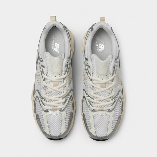 New Balance 530. Top view of silver metallic and linen sneakers showing cream laces, padded tongues and mesh toe boxes.