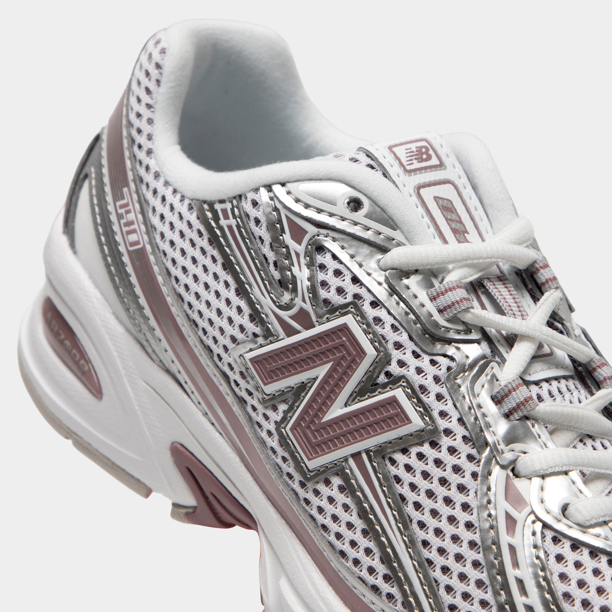 New Balance 740. Close-up of silver metallic, raincloud and pebble sneaker showing grey laces, mesh panels, layered overlays and N logo.