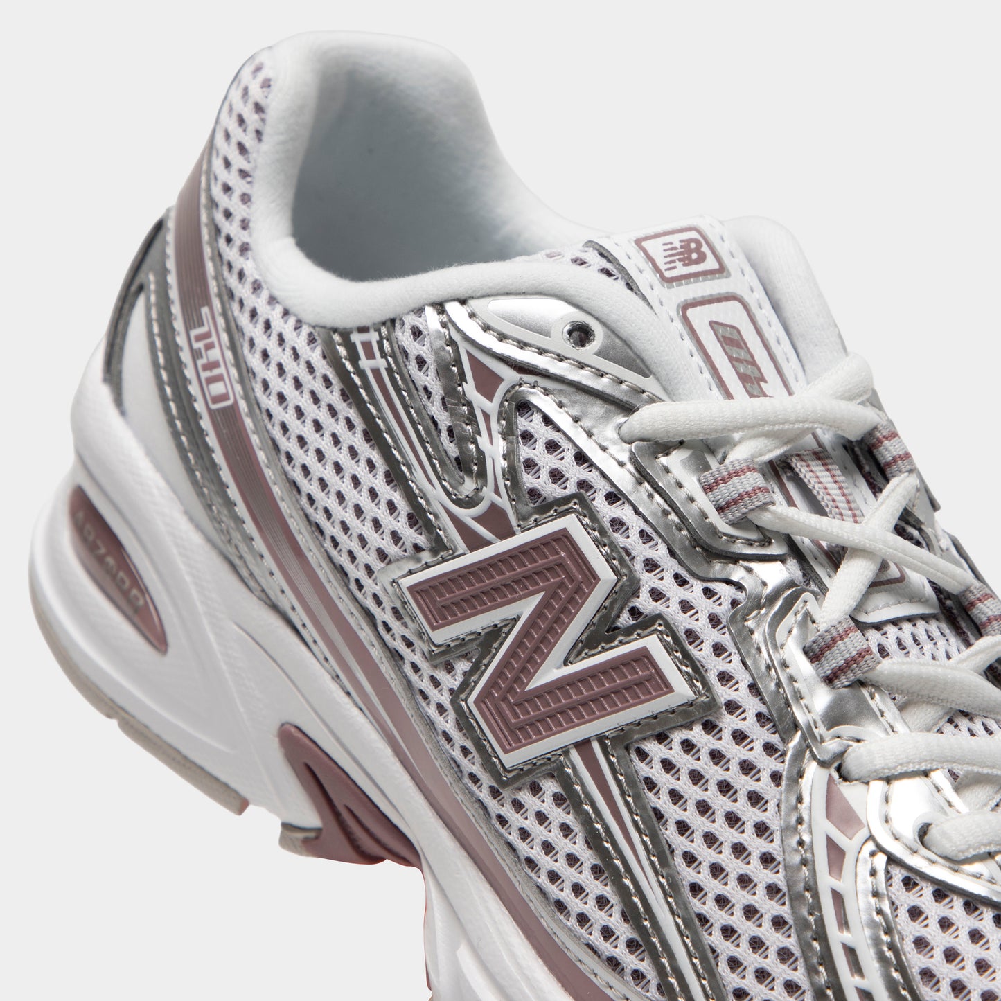 New Balance 740. Close-up of silver metallic, raincloud and pebble sneaker showing grey laces, mesh panels, layered overlays and N logo.