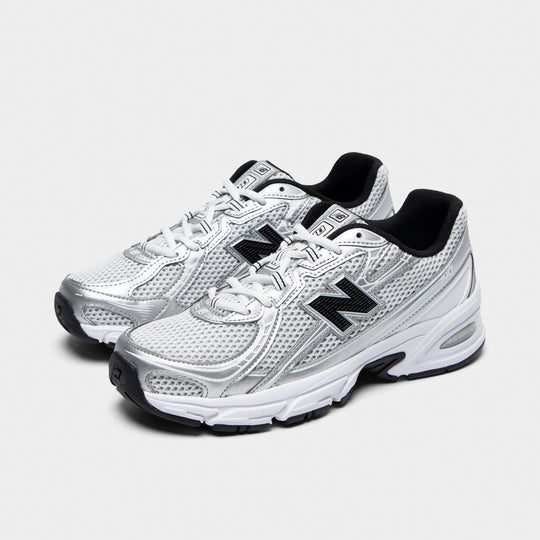 New Balance 740. Three-quarter view of white, silver metallic and black sneakers with white laces, layered overlays and black N logos.